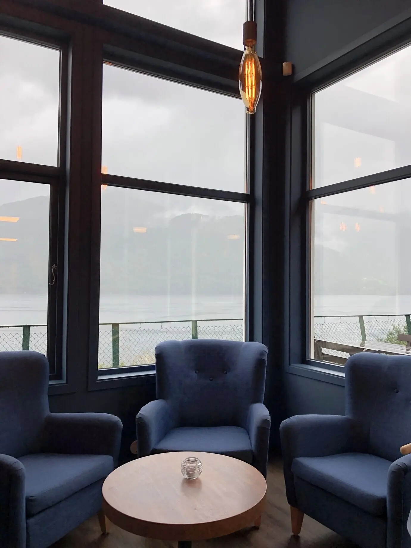 Hochformataufnahme von Sesseln um den Tisch hinter den Fenstern.